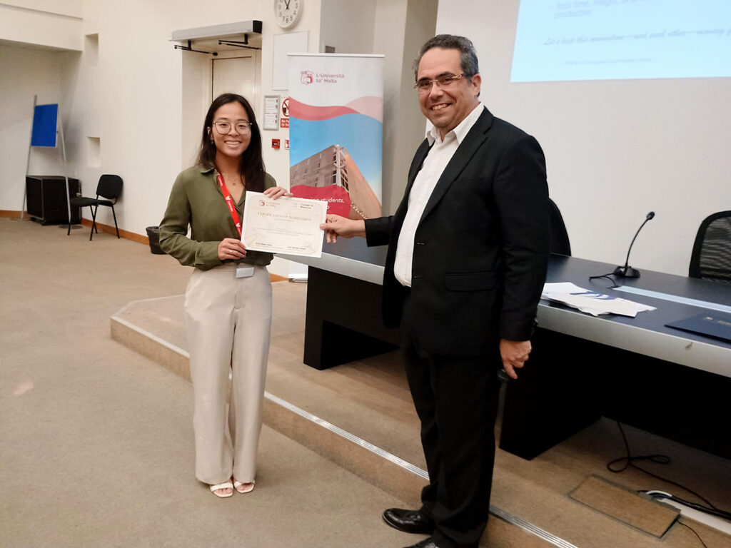 Second-year med student Riley Nguyen receives a certificate of achievement for presenting her research at the global health summit from Dr. Neville Calleja, University of Malta professor of public health