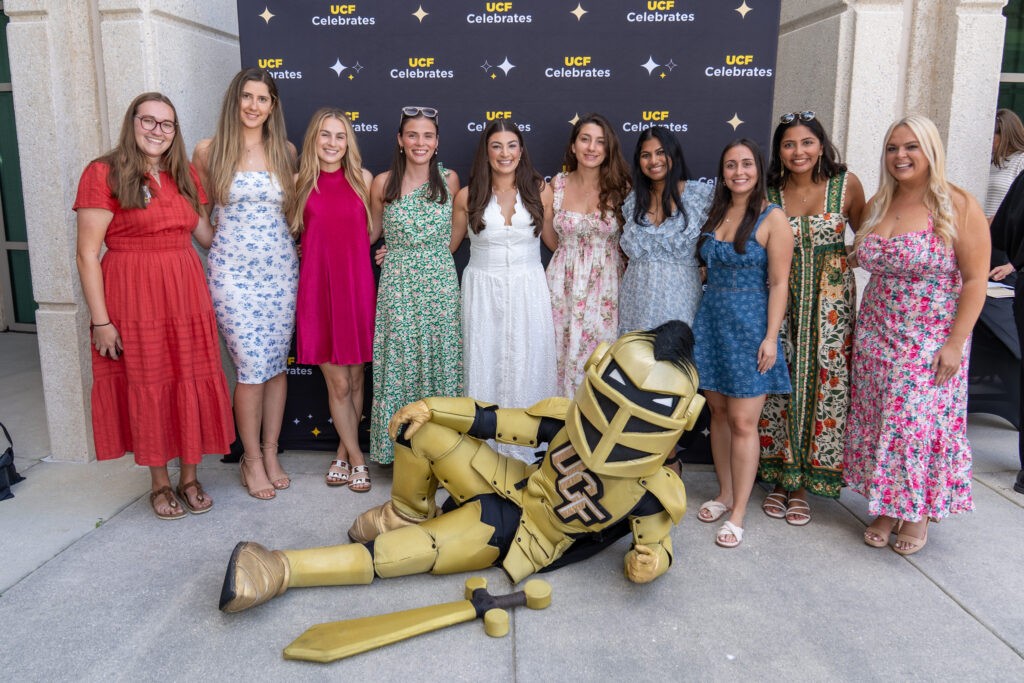A group of students posing with Knightro, who is laying at the bottom.