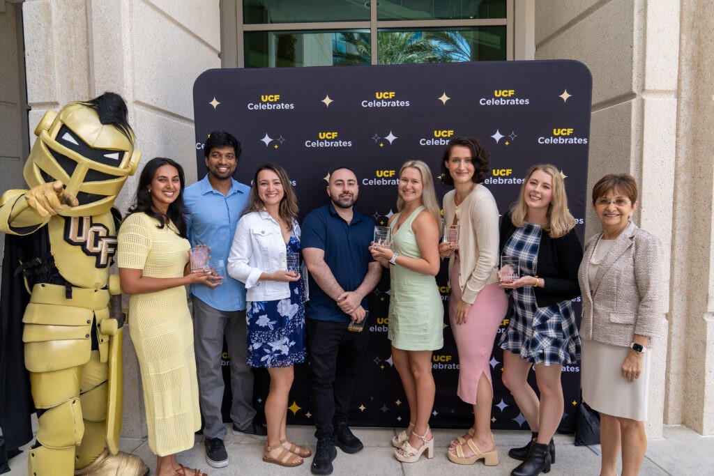 The group of students who were recognized for maintaining A's throughout all of med school pose with Knightro and Dean German. 