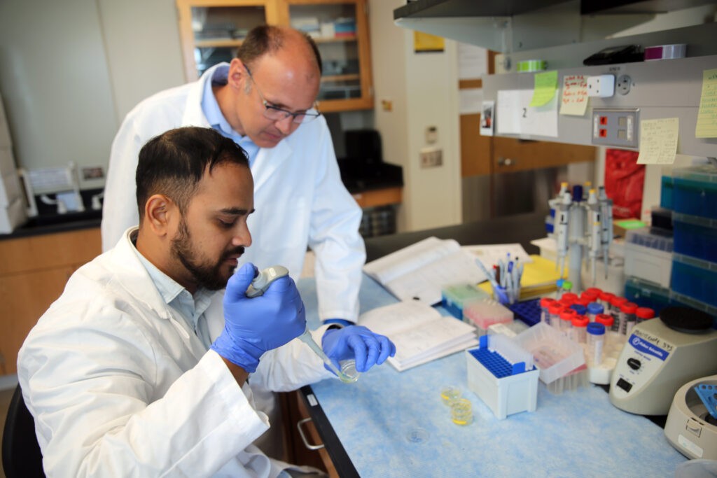 A professor watching over a student pipetting.