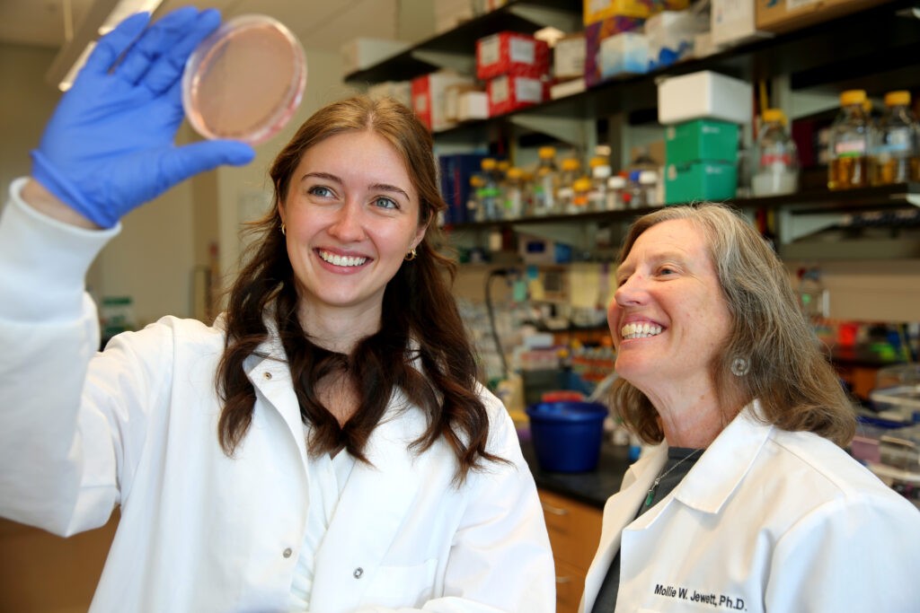 A student and scientist examine a bacterial plate together.